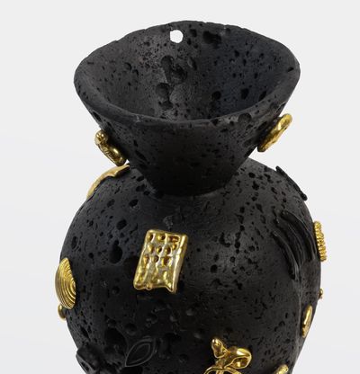 Black volcanic rock sculpture with gold and black details