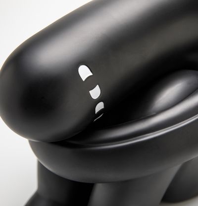Black sculpture of a figure curled up sitting on the ground