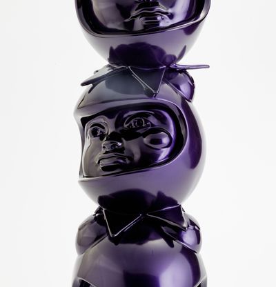a purple sculpture of three heads in custom helmets stacked on top of each other by Hebru Brantley - close up middle