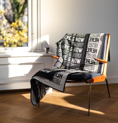 Blanket draped on mid-century armchair next to window