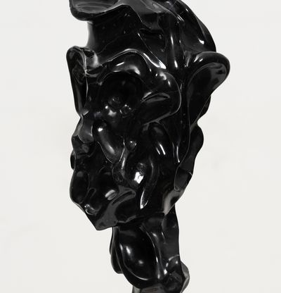 black marble sculpture resembling a face on a bronze pole by Kevin Francis Gray - close up