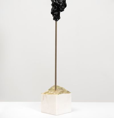 black marble sculpture resembling a face on a bronze pole by Kevin Francis Gray - side view