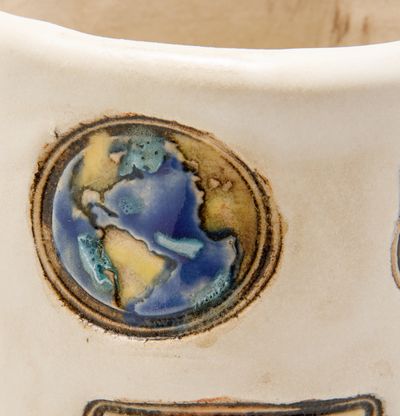 close up of glazed ceramic pot stamped with planet earth motif