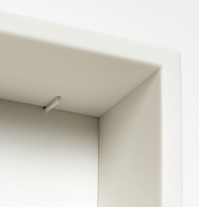 Corner of white resin frame, with small white hanging detail visible close to the corner