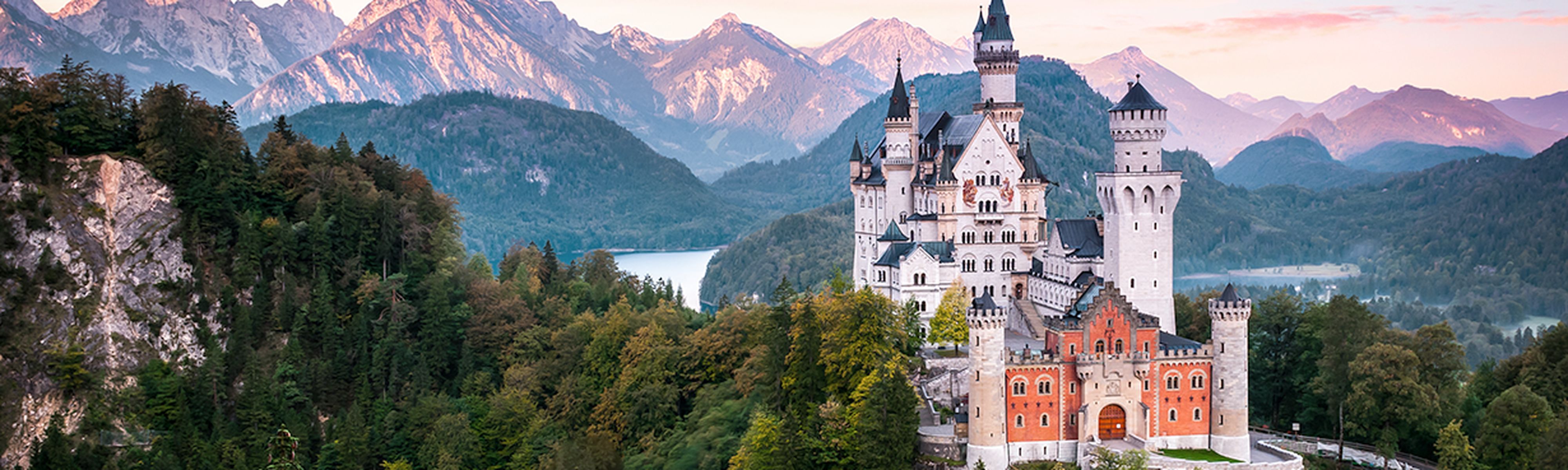 Neuschwanstein Castle at sunrise with panorama of Alps