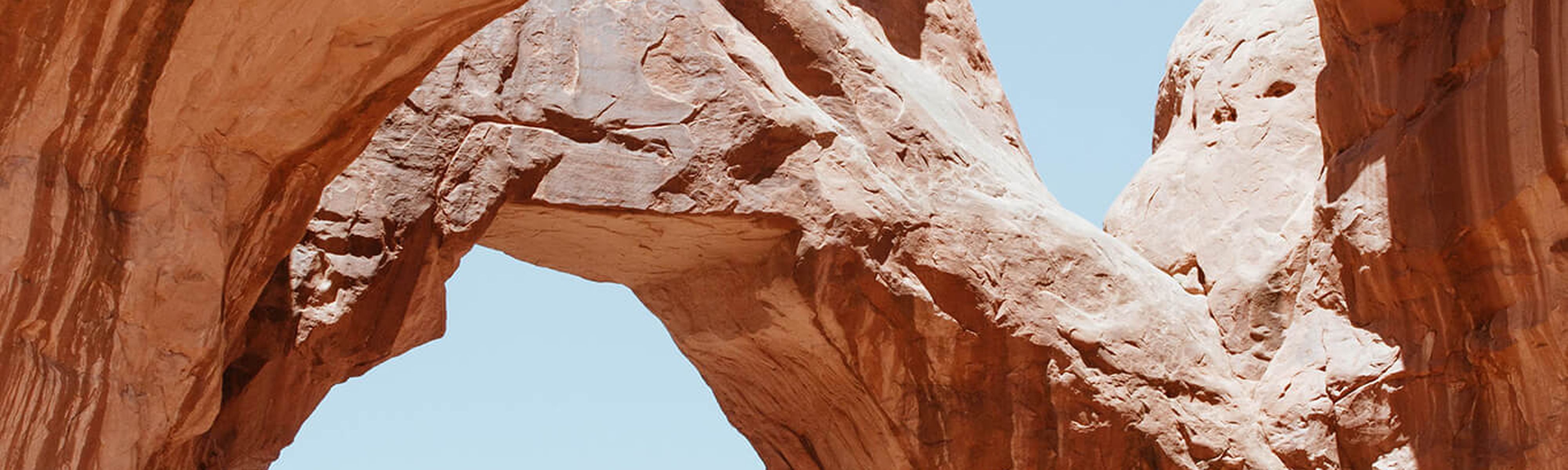 person standing on under double arch in moab utah