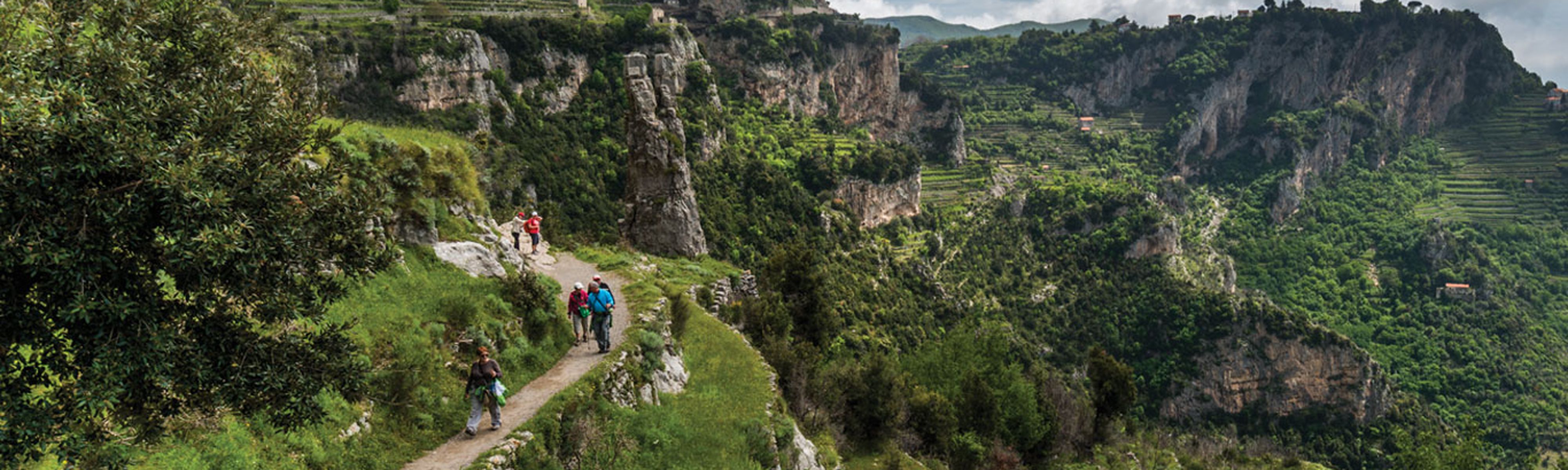 people walking along a cliff in italy