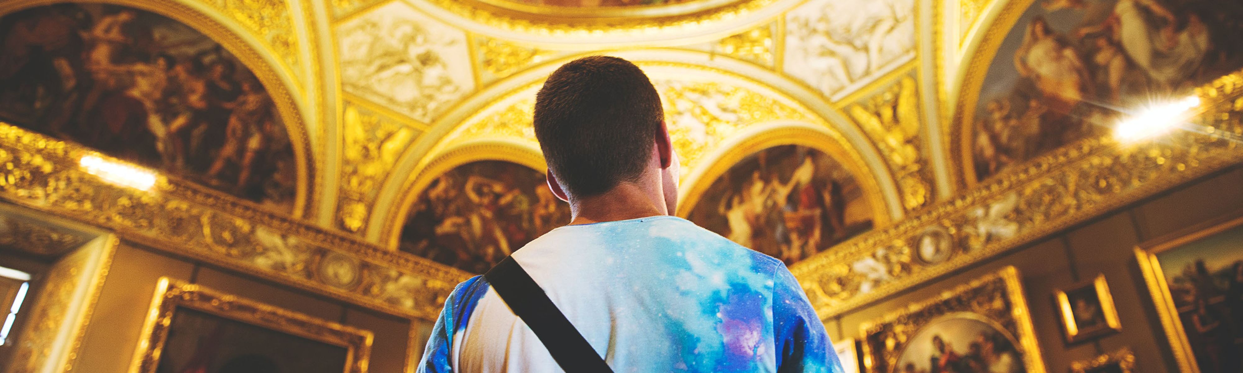 man looking up at gold painted ceiling in a basilica in florence italy