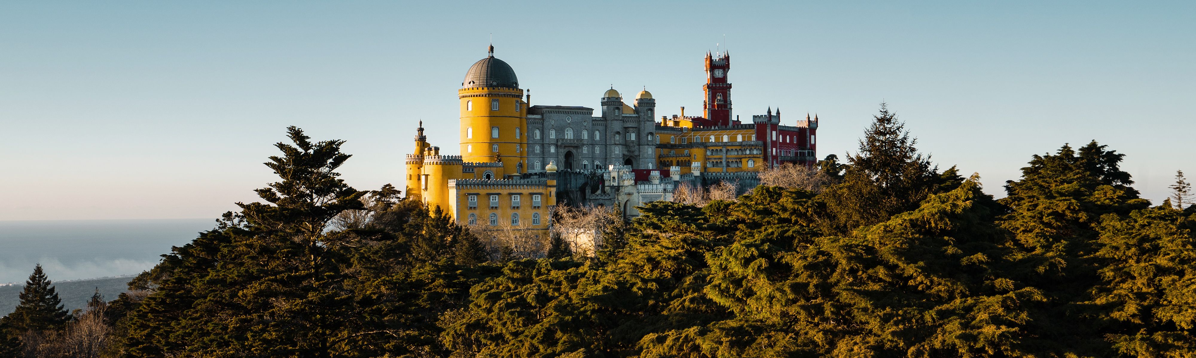 yellow purple and red pena palace surrounded by lush trees in sintra portugal
