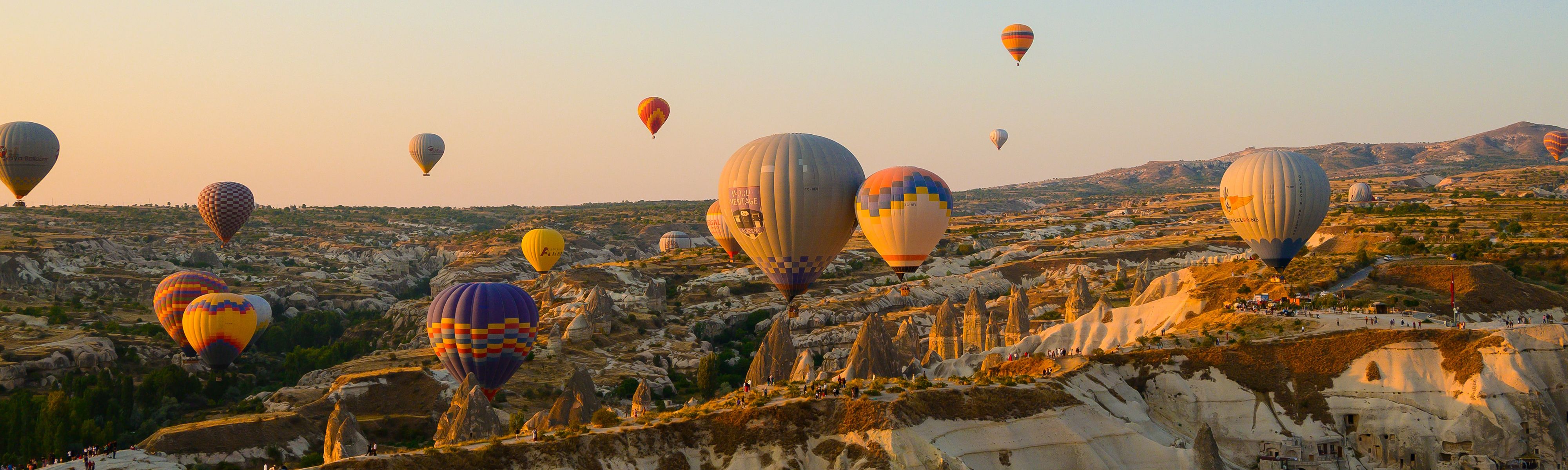 hot air balloons floating above mountains in turkey at sunset