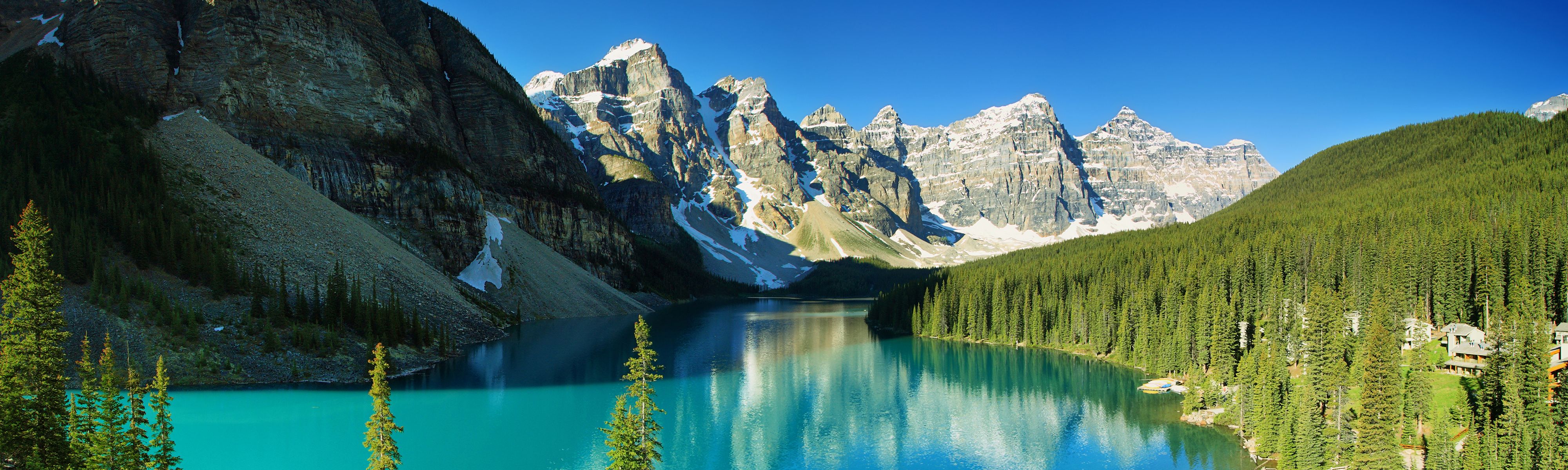 snow capped canadian rockies mountains surrounding bright teal lake and evergreen trees