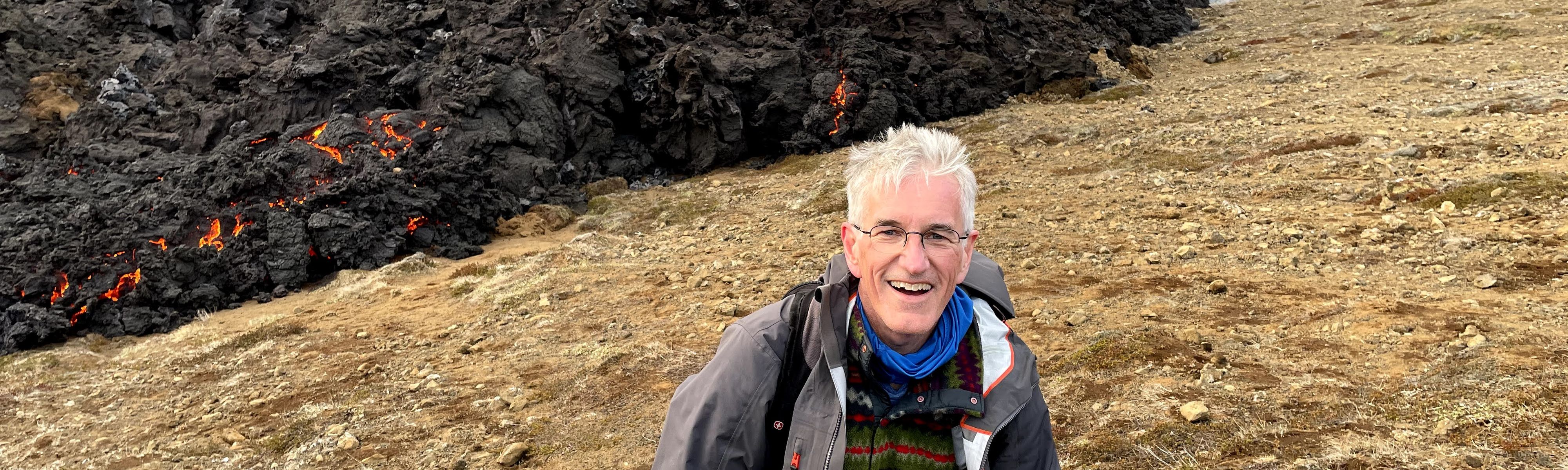 traveler smiling at camera in front of lava from volcano in iceland