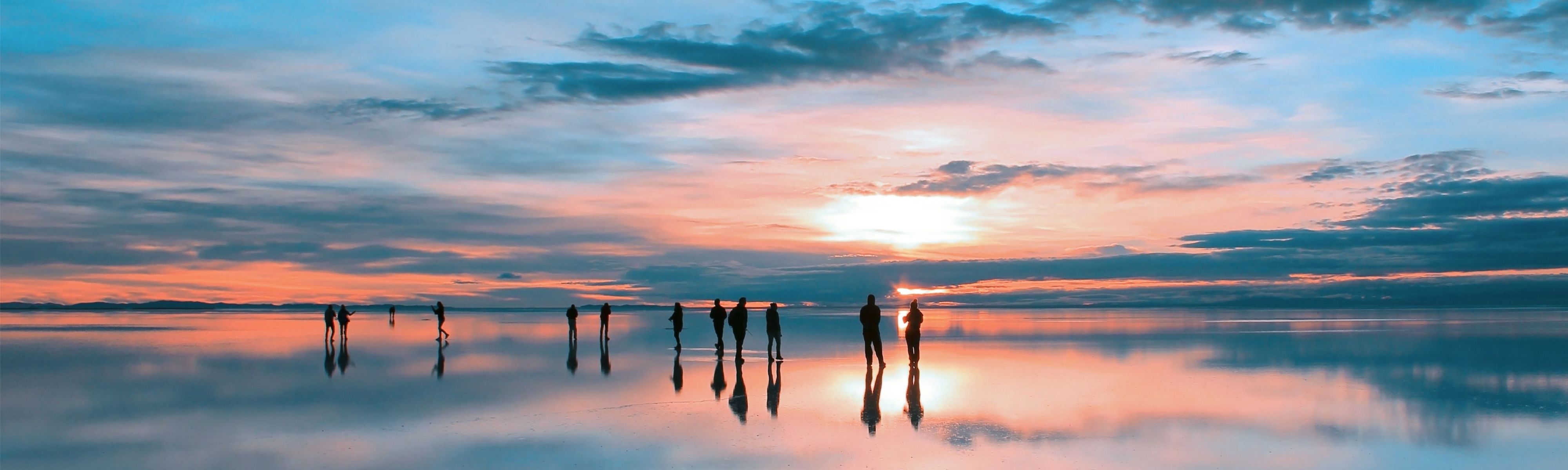 people walking around bolivian salt flats at sunset