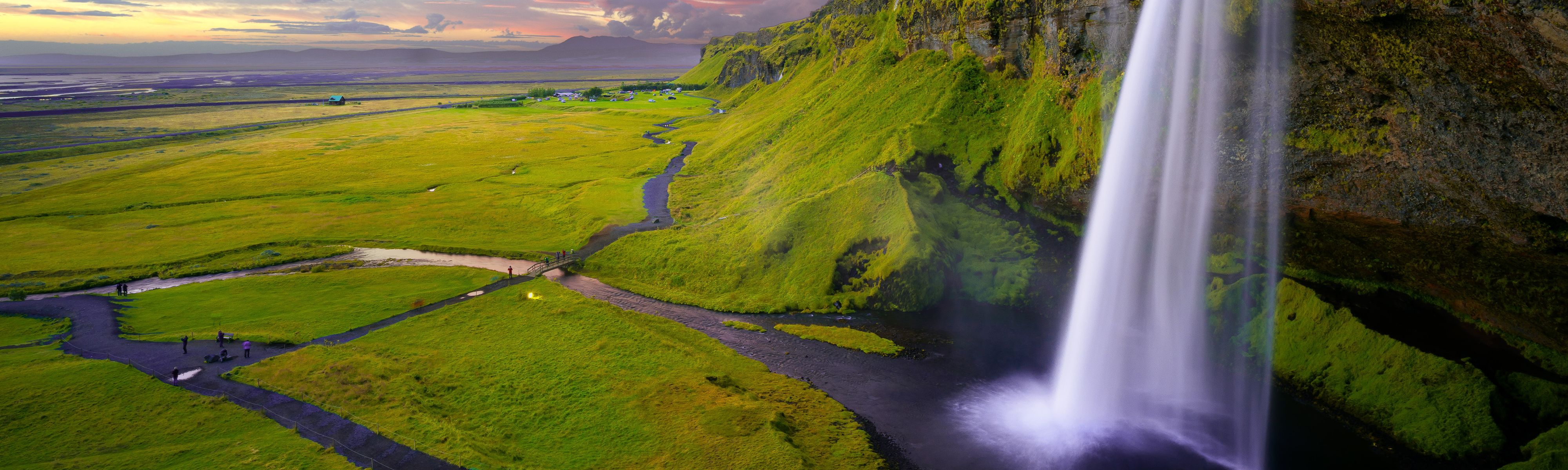 waterfall cascading over green lush landscapes in iceland