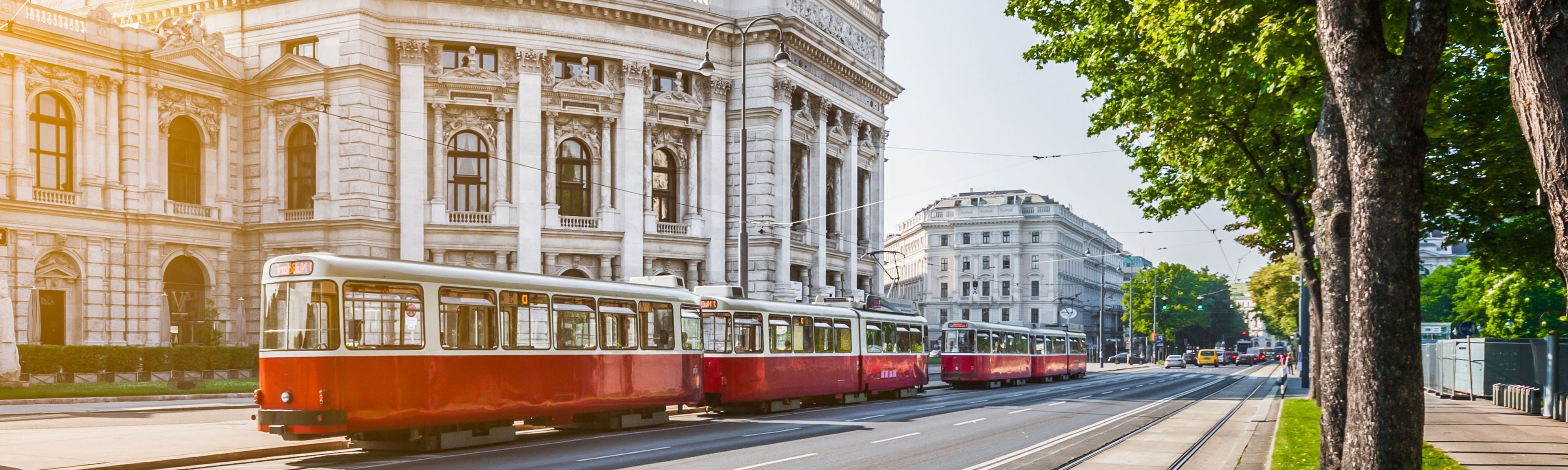 red cable cars riding down street in vienna budapest in front of wiener ringstrasse