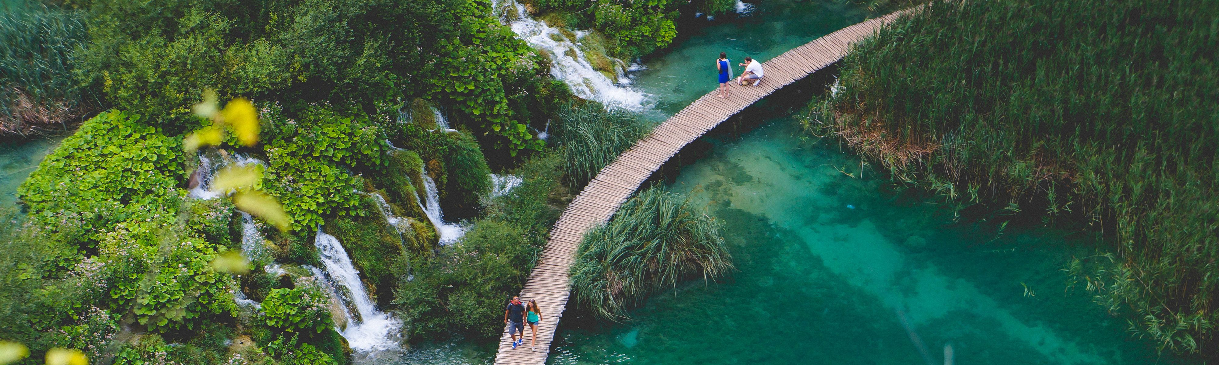 people walking along wooden bridge in Plitvice lakes national park in croatia