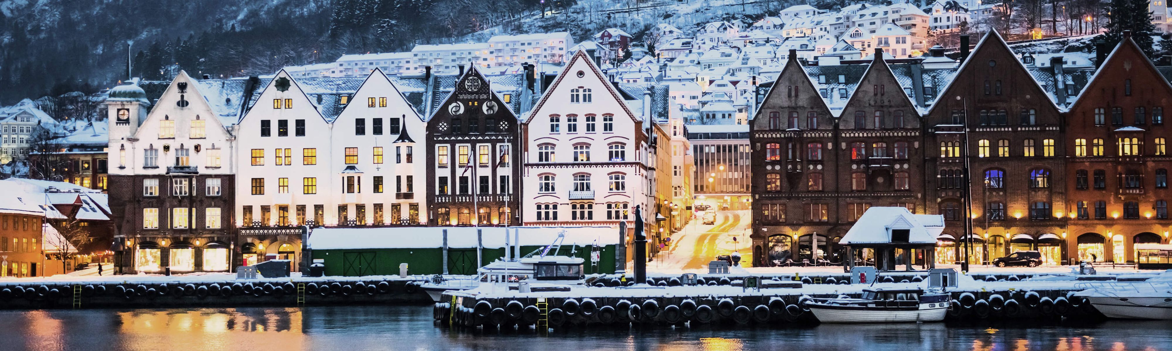 snow capped buildings in bergen norway during the evening