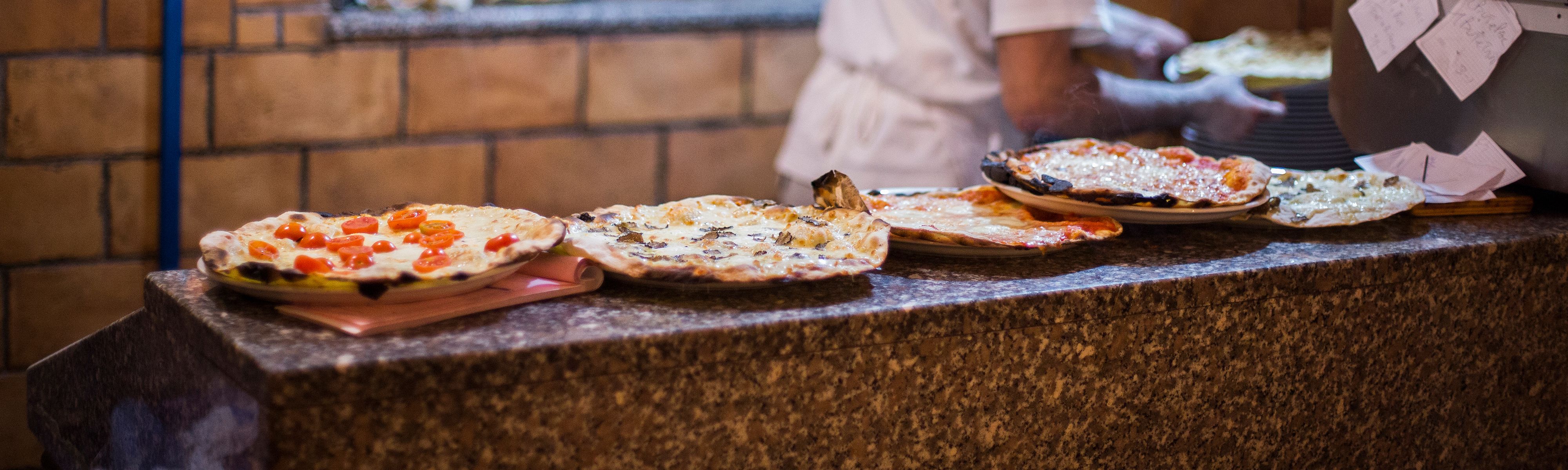 five italian pizzas on a granite shelf in a kitchen