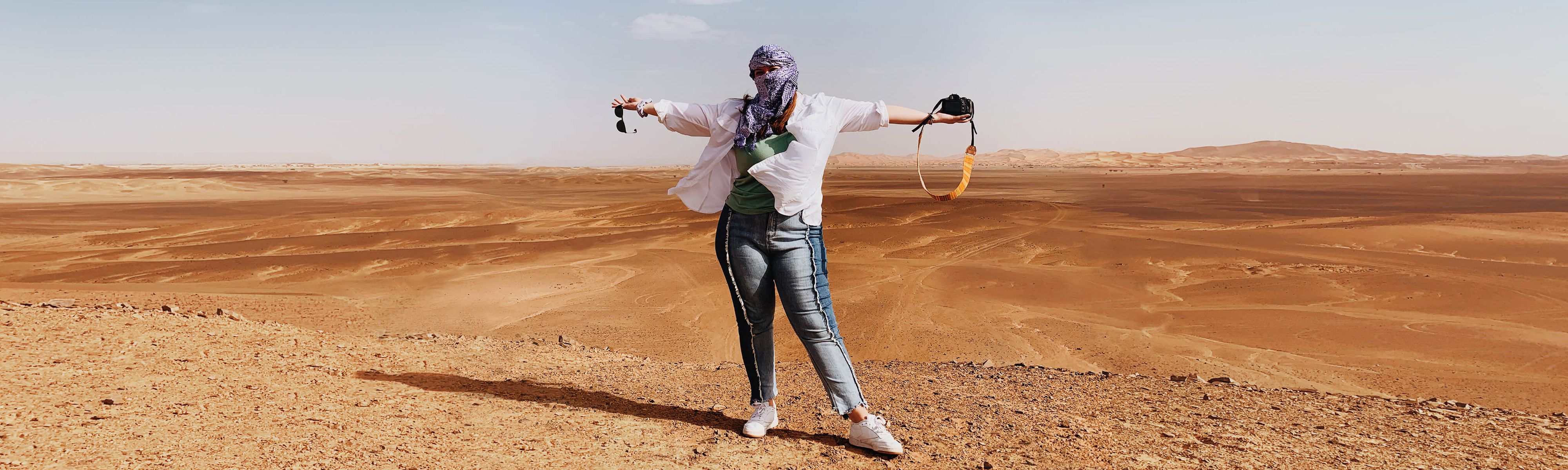 female traveler holder her arms up in the sahara desert in morocco
