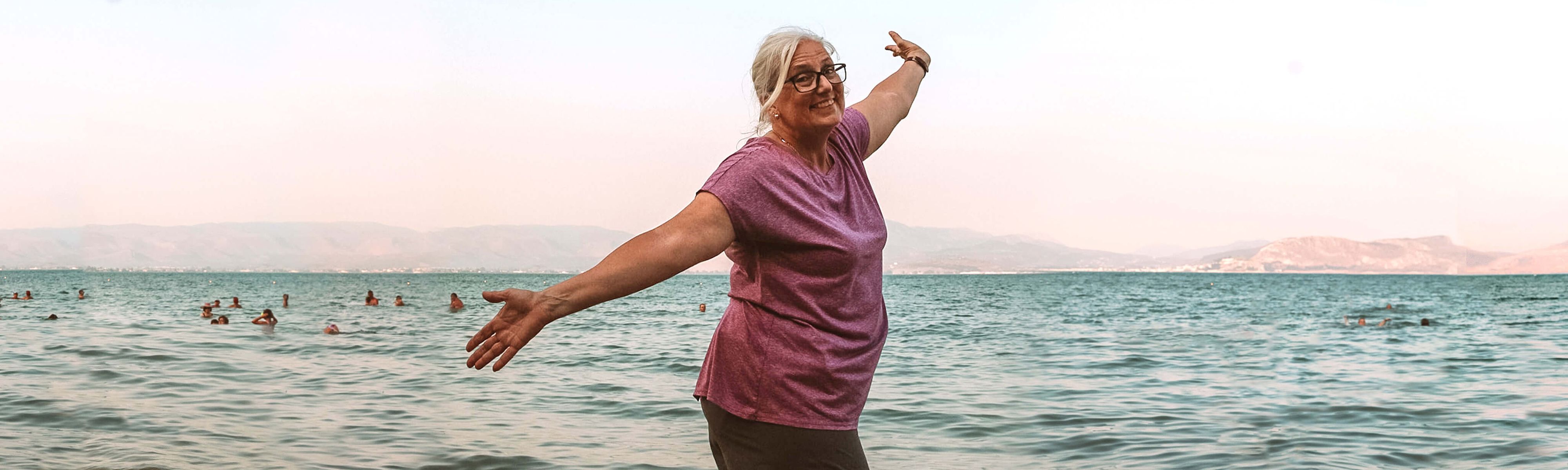 woman hands in the air at the beach in nafplio in greece