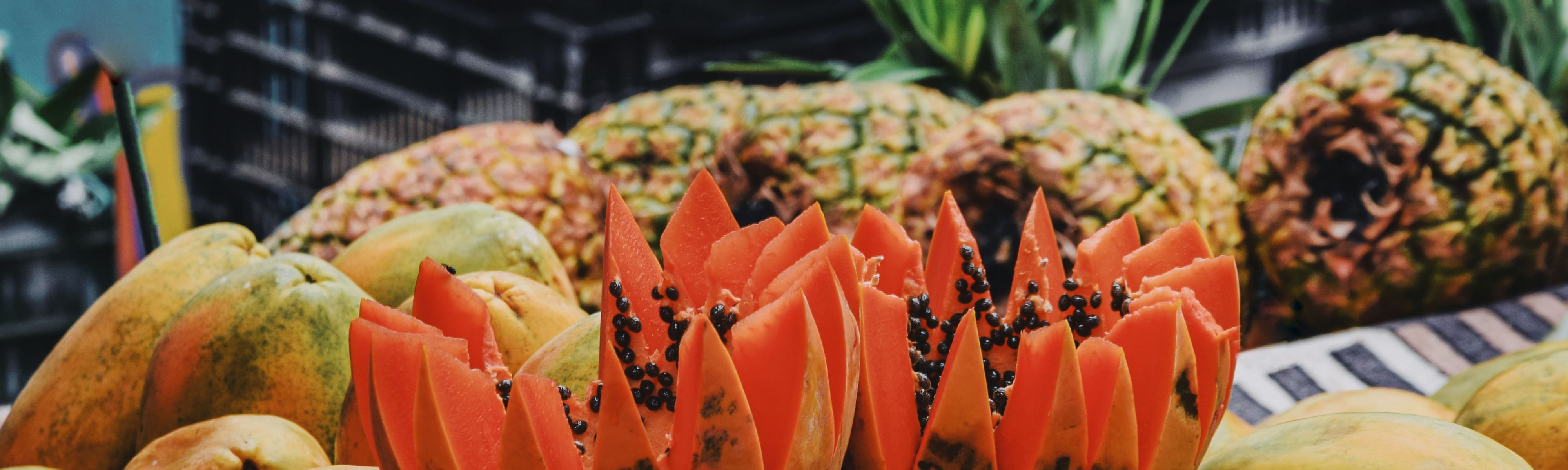 papaya cut up on table surrounded by costa rican pineapples