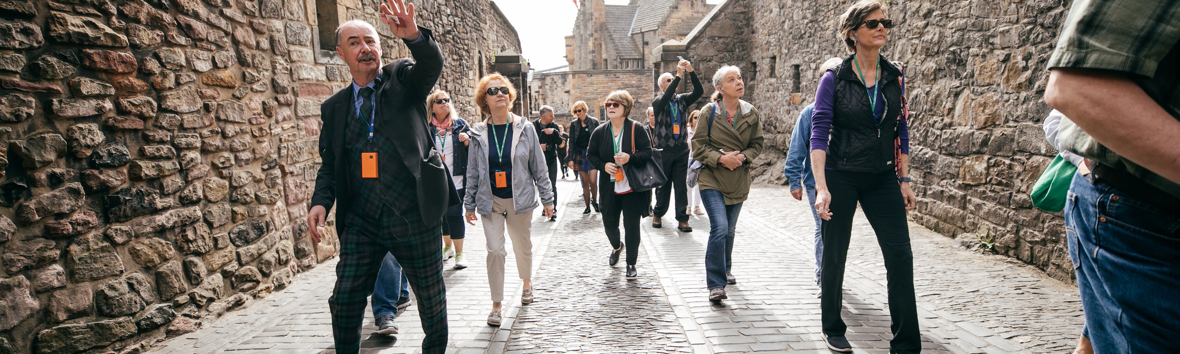 tour group walking down cobble stone path in scotland with local guide