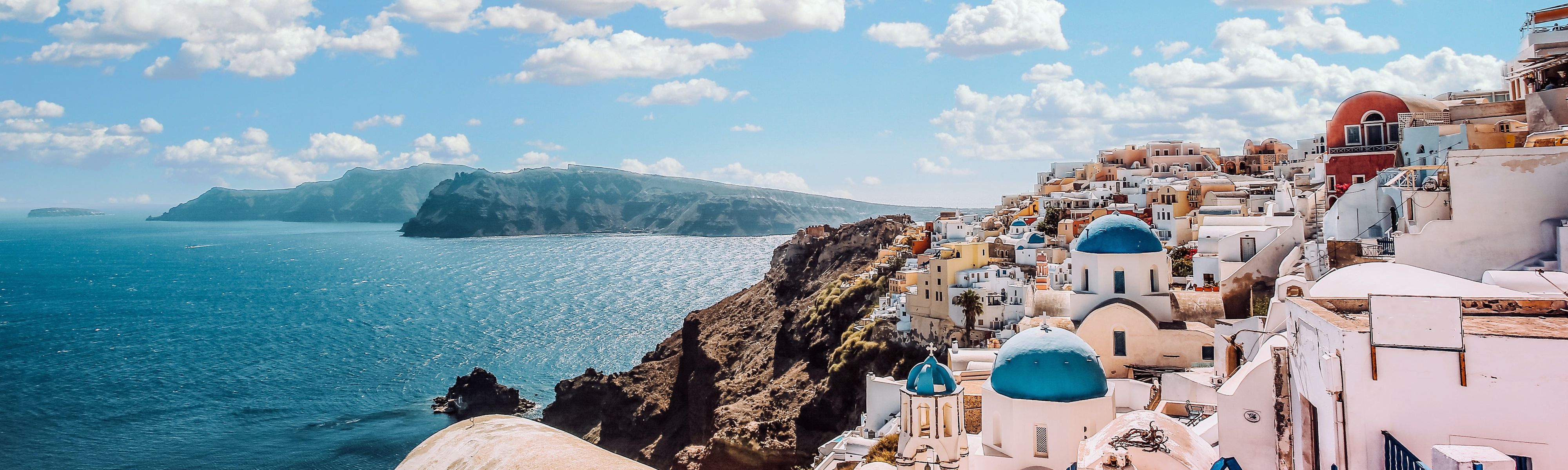 blue domed buildings along the cliffs of santorini in greece