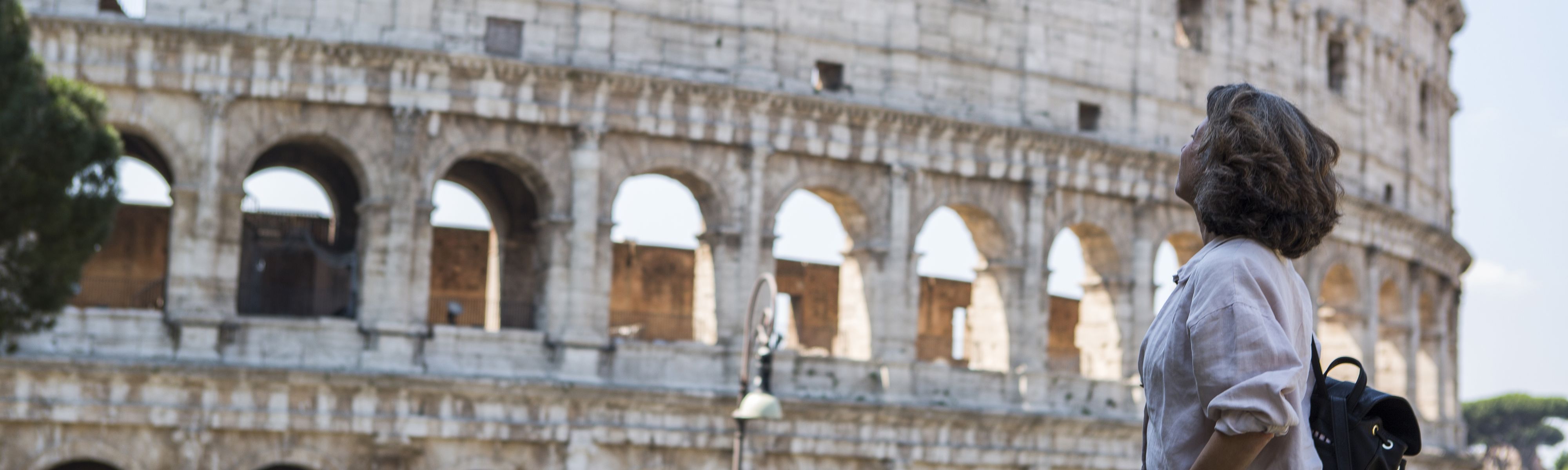 female solo traveler looking up at the colosseum in rome italy 
