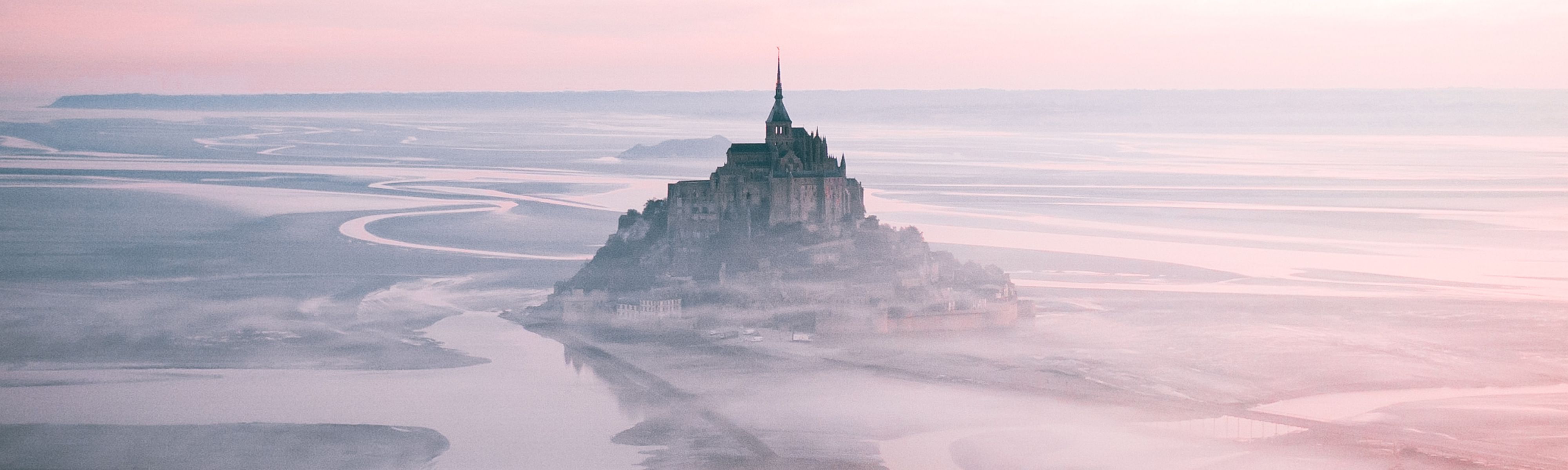 Mont Saint-Michel surrounded by fog at dusk in france