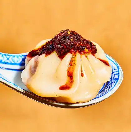 Image of a dumpling on a spoon with Sichuan Chili Crisp on top