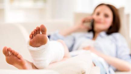 Osteoporose-Patientin liegt mit gebrochenen Fuß auf Couch