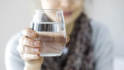 Frau hält Glas Wasser in der Hand zum Trinken