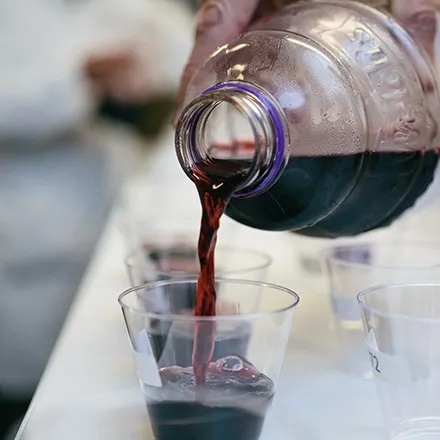 Hand pouring a bottle of Welch's 100% Concord Grape Juice into a cup.