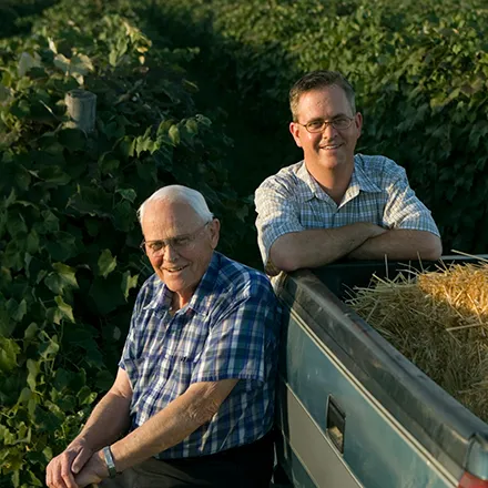 Son and Father on their farm standing at their truck