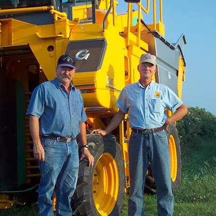 Two farm workers standing next to tractor 