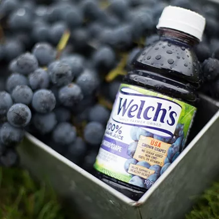 Bottle of Welch's 100% Grape Juice in a basket of grapes