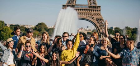A group of travelers posing for a photo in front of the Eiffel Tower in Paris