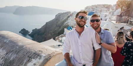 Two travelers standing on a cliffside in Santorini