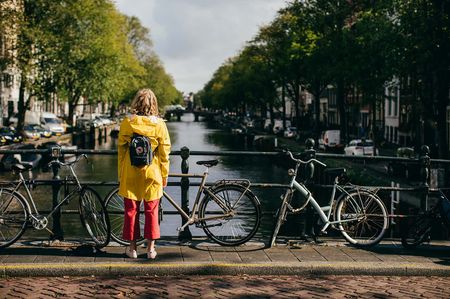A girl standing alone in Amsterdam overlooking a canal.