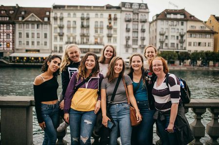 A group of girls posing for the camera in front of a scenic city canal in Switzerland.
