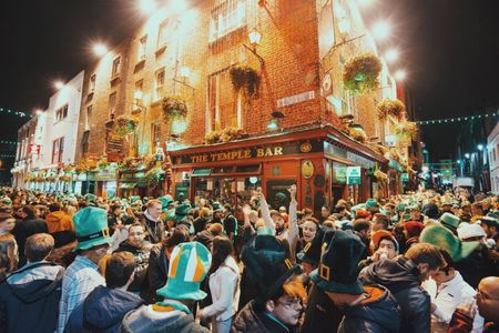 A group of people dressed up in green wearing leprechaun hats are gathering outside a pub in Dublin.