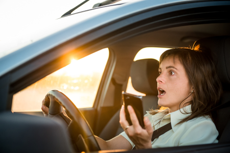 vyděšená řidička za volantem s mobilem v ruce 
