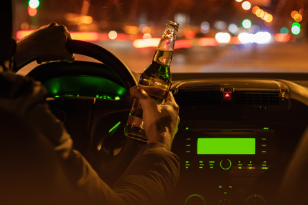 řidič za volantem večer s láhví piva v ruce