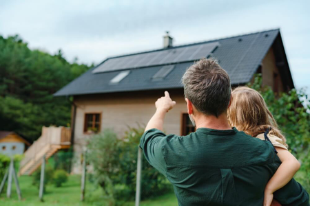 Otec s dcerou si prohlíží dům se solárními panely