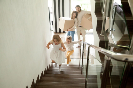 Ceny nemovitostí - Podlaží, dvě děti na schodech, rodiče s krabicemi pod schodami