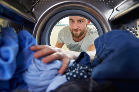 Muž vytahuje prádlo z pračky