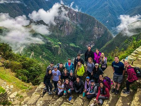 A group of travelers standing at the top of Machu Picchu in Peru.