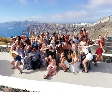A group of girls in a sorority enjoying wine on a Santorini cliffside