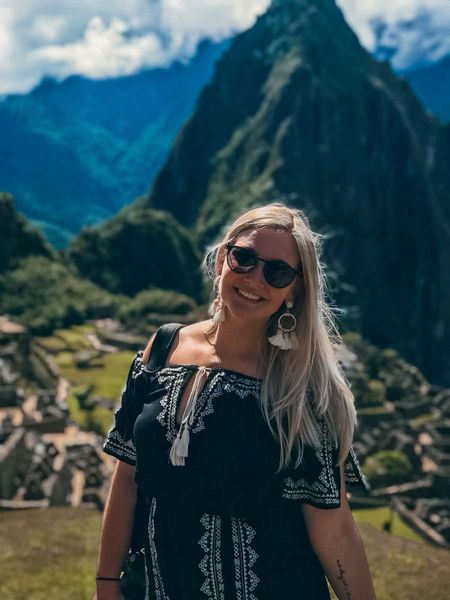 A young woman posing with Machu Picchu in the background.