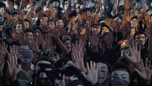 a large mass of people in a crowd all holding up their hands and wearing similar white masks